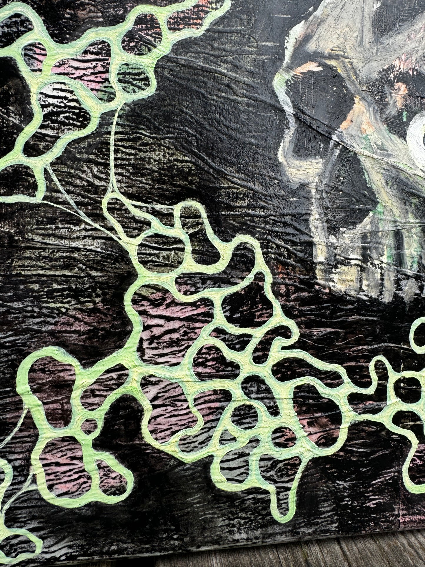 Close up in lower left corner of a painting that is is pastel pink, green, yellow, orange, and black. There is wrinkly texture, a skull with an eyeball, a dagger, and circular blobs