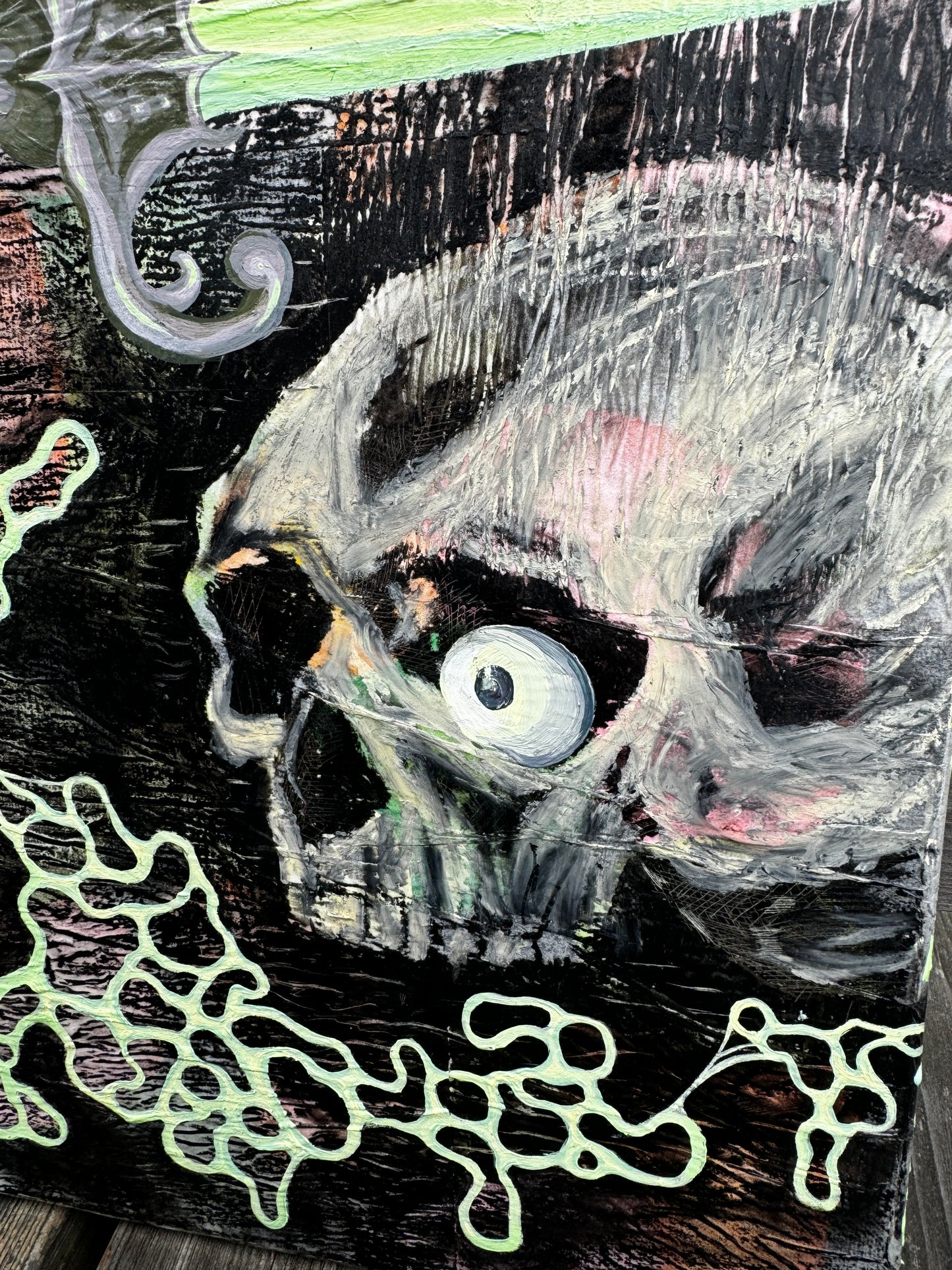 Close up of skull from pastel pink, green, yellow, orange, and black painting. There is wrinkly texture, a skull with an eyeball, a dagger, and circular blobs