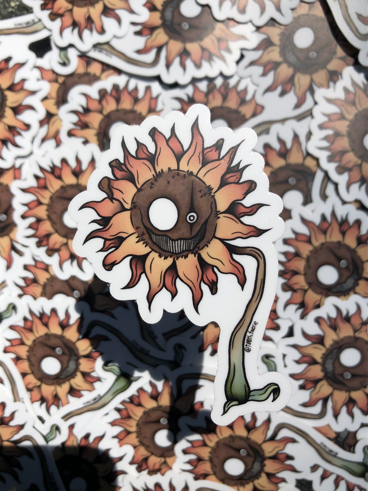 Product shot of a vinyl sunflower sticker. The sunflower has a creepy face on it.