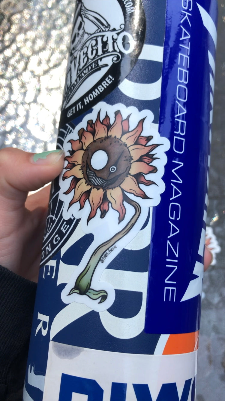 photo of a water bottle with a vinyl sticker on it of a creepy faced spooky sunflower.