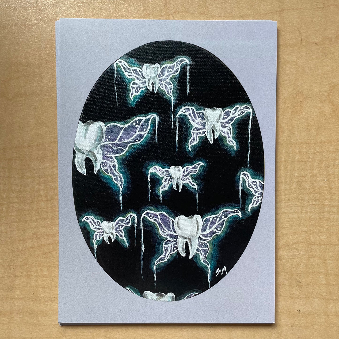 Prints of "tooth fairies" acrylic painting - teeth with glowing purple and teal fairy or insect wings suspended against a black background. Painting is an oval shape with a lavender border.