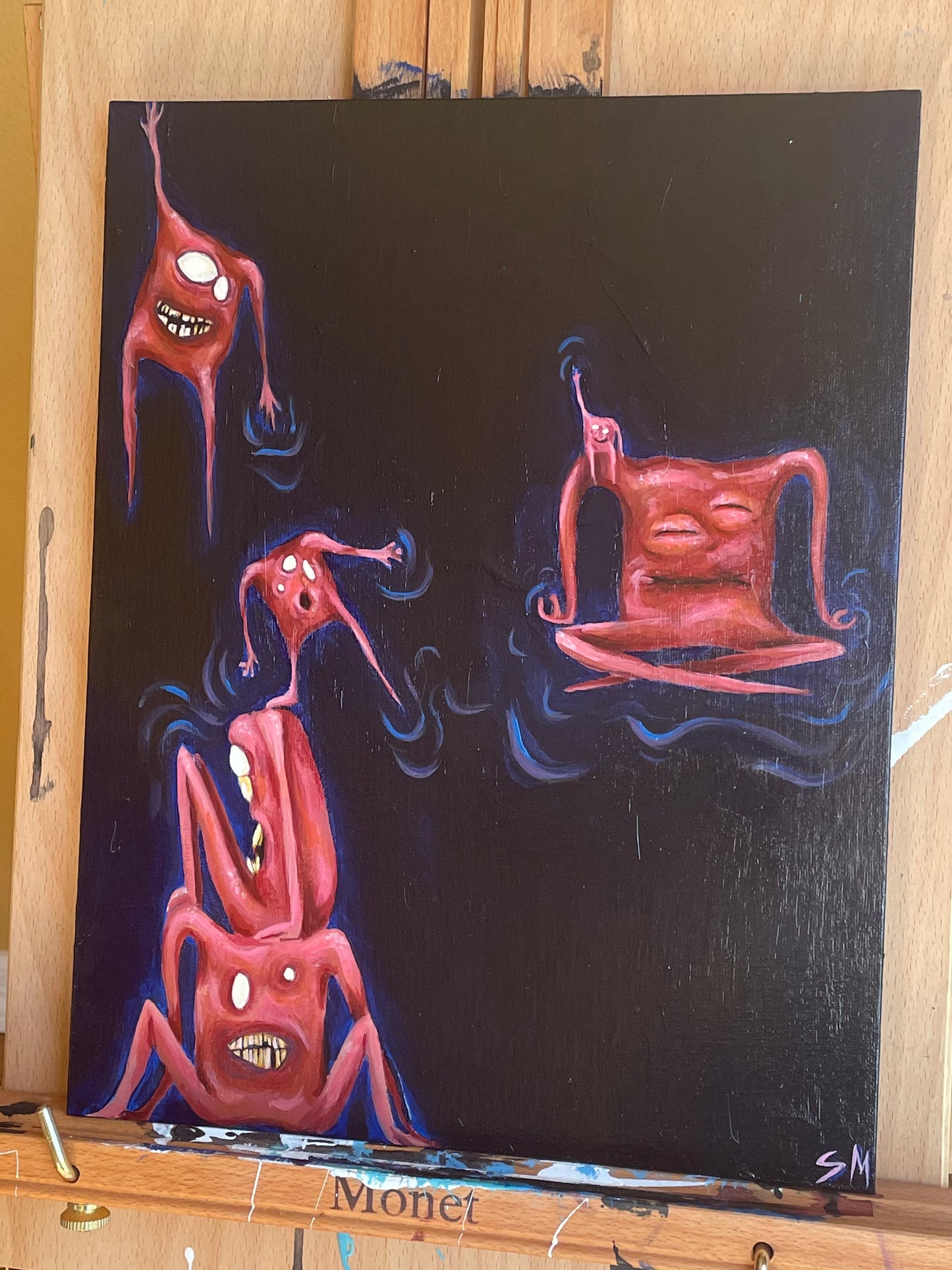 Straight on photo of a whimsical acrylic painting on a wooden easel. Painting is of six pinky orange square-shaped monsters/critters/creatures sitting, meditating, hanging, and balancing in space.