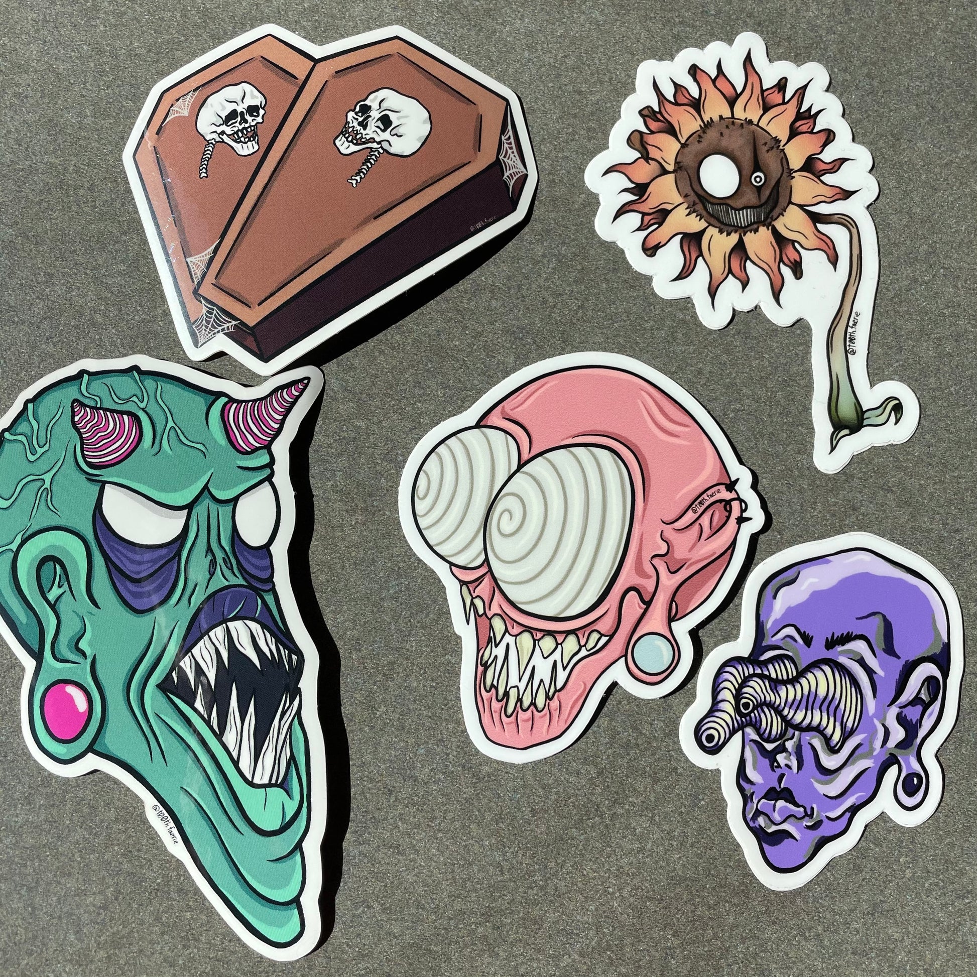 5 T00thFaerie Art vinyl stickers for water bottles, binders, phone cases, students, horror movie fans, and fun. One skull coffin sticker, three monster head stickers, one spooky sunflower sticker.