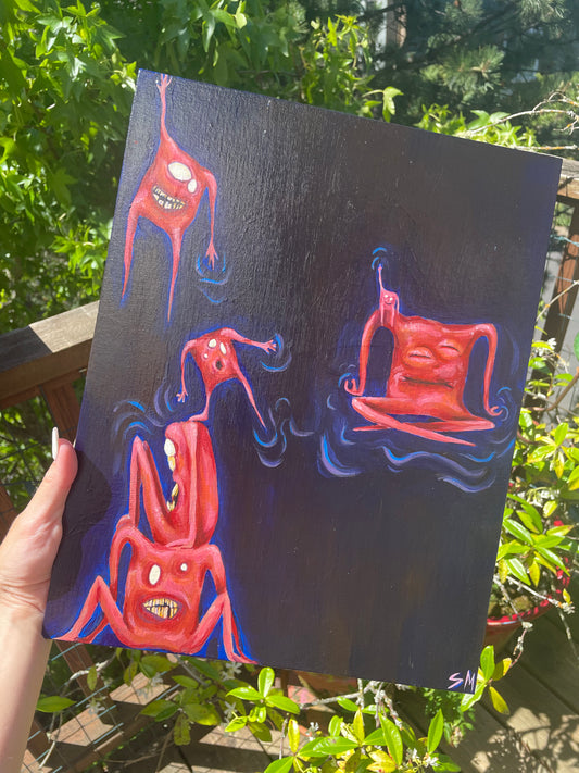Holding a whimsical acrylic painting in front of plants. Painting is of six pinky orange square-shaped monsters/critters/creatures sitting, meditating, hanging, and balancing in space. 